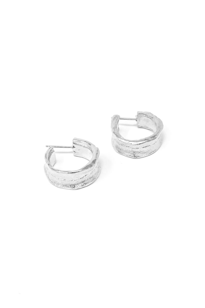Small hand-stitched huggie earring in 14k white gold. Huggie hoop earrings with a textured surface created by casting fabric into metal. Handmade by local jewelry designer, Nina Berenato, in Austin, Texas.